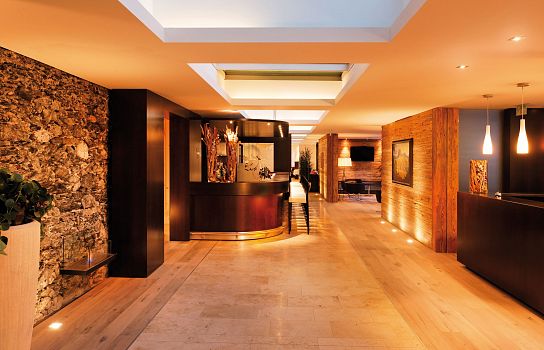 Elegante Hotellobby mit moderner, warmer Beleuchtung. Holzboden, kunstvoller Empfangstresen und kunstvolle Dekorationen schaffen eine einladende Atmosphäre.